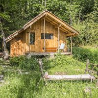 Devant la cabane, une chaise longue improvisée avec les éléments d'un vieux char à foin Cabane de la forêt